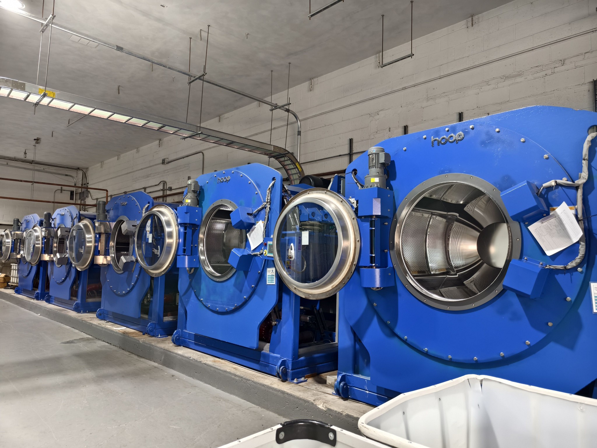 Row of 150kg industrial washer extractors at a commercial laundry facility